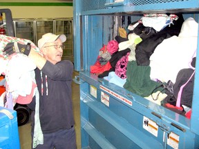 Goodwill Industries employee Don Brissette prepares to throw an armful of used clothing into a compactor the company has at its new recycling operations in Chatham, Ontario on Friday January 11, 2013. VICKI GOUGH/ THE CHATHAM DAILY NEWS/ QMI AGENCY