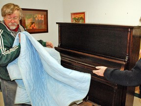 John Hall, curator of Vulcan’s former piano museum, donated a 100 year old piano to the Vulcan Centennial Committee. Here, committee co-chair Louise Schmidt takes a look as Hall removes a protective cover after moving the instrument to the committee’s office. 
Simon Ducatel/Vulcan Advocate
