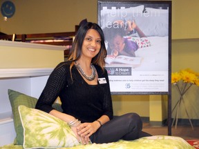 Loveen Sanders, owner of Ashley Furniture HomeStore in Grande Prairie, sits on one of the two single beds and bedding that will soon be given to a local family as part of the “A Hope to Dream” program. (Patrick Callan/Daily Herald-Tribune)