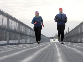 Laurie Lyle (right), president of the Grande Prairie Run Walk Club, runs with friend Colleen Gagnon along the pedestrian bridge just south of South Bear Creek Sunday morning.  Lyle says this is the time of year action starts to heat up for the Run Walk Club and the city is warning people about the icy conditions that are plaguing many of the trails. (Adam Jackson/Daily Herald-Tribune)