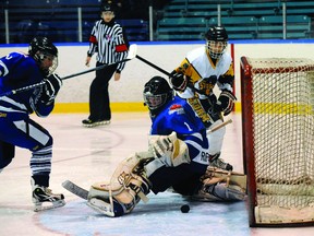 Woodstock goaltender Micheal Roefs reaches for the puck as defenceman Bryce Cadwell and Simcoe's Conner Robinson look on during a game at Talbot Gardens in Simcoe Sunday night. The Storm won 6-2 handing Woodstock their 13th straight loss. (SARAH DOKTOR, QMI Agency)