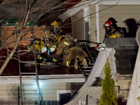 Firefighters open the roof of a house on Sydenham Street Monday night to get at the flames. The fire caused $81,000 in damage to the downtown Kingston home.
Julia McKay