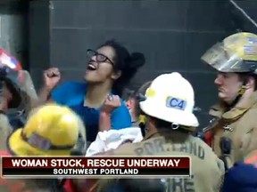 Portland firefighters rescue a woman who fell into an 8-inch gap between a building and a parking structure on Wednesday. (KPTV-FOX screengrab)