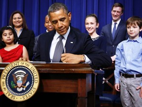 U.S. President Barack Obama signs executive orders on gun violence flanked by 8-year old letter writer Hinna Zeejah (L), 10-year old letter writer Taejah Goode (3rd L), 11-year old letter writer Julia Stokes and 8-year old letter writer Grant Fritz (R) during an event at the White House in Washington, January 16, 2013. REUTERS/Jason Reed