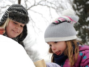 Addy Peach, 5, takes over briefly for Lawrence House volunteer Jessica Curtis, 18, as she works on the organization's snow sculpture at Snowfest Friday Jan. 18, 2013 in Sarnia, Ont. (TYLER KULA, The Observer)