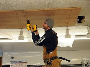 Sean Johnson helps cover a hole in the ceiling at Blackmans Butcher Shop. The store has been temporarily closed since Sunday after last week’s warm weather caused water to leak in through the roof. (Patrick Callan/Daily Herald-Tribune)
