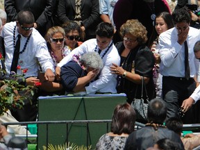 Family members console former San Diego Chargers player Junior Seau's mother Luisa Seau (C) as his casket is lowered at his burial in Oceanside, Calif., May 11, 2012. (REUTERS/Denis Poroy)