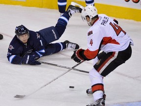 Winnipeg Jets' Kyle Wellwood (L) takes a shot past Ottawa Senators' Chris Phillips as he falls to the ice during the second period of their NHL hockey game in Winnipeg January 19, 2013. REUTERS/Fred Greenslade  (CANADA - Tags: SPORT ICE HOCKEY)