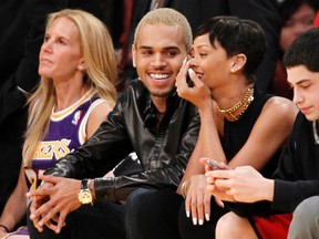 Recording artists Chris Brown (L) and Rihanna sit together courtside at the NBA basketball game between the New York Knicks and Los Angeles Lakers in Los Angeles December 25, 2012. REUTERS/Danny Moloshok