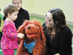 RYAN PAULSEN     Emily Phillips, one-and-a-half, says hello to “Bingo,” and Laura Demont, stars of the Friends and Neighbours Club puppet show. The show was at the Ontario Early Years Centre in Pembroke for its Family Literacy Day party on Friday morning.