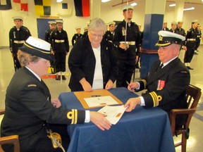 Lt. Carol Weston, left, the new commanding officer of the Royal Canadian Sea Cadet Corps 'Repulse', took over Saturday in a ceremonial sword exchange and signing from outgoing Lt. Cmdr. David Anderson, right.  Sarnia-Lambton MP Pat Davidson, centre, assisted and was reviewing officer. CATHY DOBSON/THEOBSERVER/QMI AGENCY.