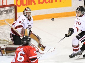 Guelph Storm defenceman Saverio Posa, right, tries to grab the puck deflected off goalie Garret Sparks as Owen Sound Attack Daniel Milne, right, and Kurtis Gabriel move in during first period OHL action Saturday at the Harry Lumley Bayshore Community Centre in Owen Sound.