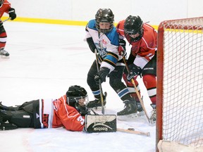 SARAH DOKTOR Simcoe Reformer
Ayr goaltender Zach St. Louis dives for the puck as Simcoe's Joel Storoschuk digs for it between Ayr's Alex Dawson during game one of their OMHA playdowns at Talbot Gardens on Jan. 29. The Warriors won 6-1.