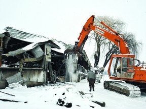 Snow cascades off the burned out shell of the Verburg family's dairy barn as Gord DeRoos begins the demolition process Tuesday morning. (DARCY CHEEK/The Recorder and Times)