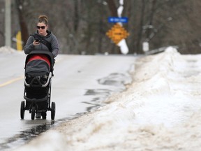 A woman pushing a stroller opts to walk on the side of the street on Tuesday January 29 in Owen Sound instead of using the slush and snow filled sidewalk.