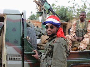A Malian soldier, with a French flag wrapped around his head, stands next to a military vehicle in the recently recaptured town of Gao January 27, 2013. (REUTERS/Adama Diarra)