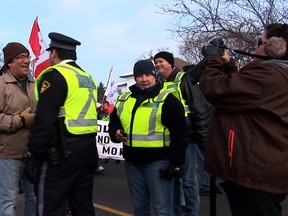 A police liason officer and a First Nations protester share a laugh during the Idle No More blockade at the Bluewaer bridge.  (Photo courtesy of documentary filmmaker Monica Virtue)