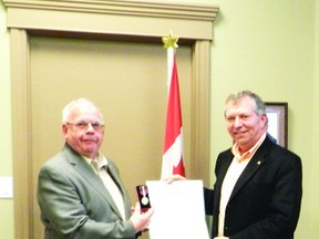 BRIAN VOSSEN Photo. Pincher Creek resident and long-time volunteer Dick Burnham (left) is recognized for his contributions to the community as he receives the Queen Elizabeth II Diamond Jubilee medal from Ted Menzies on Dec. 21.