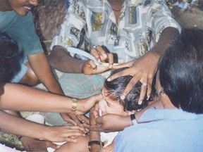 Vishal undergoes his mottai, held down and comforted simultaneously by relatives.