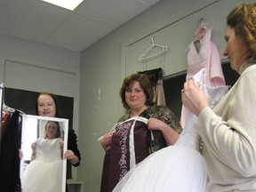 Tracy Ranick, left, and Beth Fudge, of Sarnia Lambton Business Development Corporation, watch as Debbie Anderson, of Cinderella Story of Sarnia-Lambton, looks at a dress in the mirror recently. Cinderella Story will once again be offering dresses to graduating Grade 8 and 12 students on April 12 and 13. (BARBARA SIMPSON, The Observer)