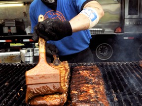Connor Reid, of London, slaps some sauce across a rack of ribs at Boss Hogs during the opening day of Ribfest, hosted by the Chatham Sunrise Rotary Club in Tecumseh Park on Friday. Aside from ribs, the three day event offers a children's area, free entertainment, food booths and an amateur rib contest. (DIANA MARTIN, Chatham Daily News)