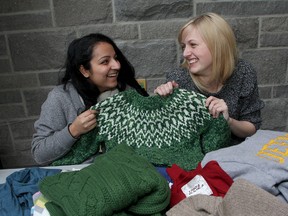 Jill Lemmen (right), the Queen's University student organizer for the World Wildlife Fund, with fellow volunteer and student Mahima Lamba as they hold sweaters to be swapped as part of WWF's National Sweater Day.
Ian MacAlpine The Whig-Standard