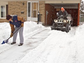 Phil Clement (right) helps his neighbour David Forbes, both of Sprucehill Drive, clear his driveway with his ATV and plough on Friday. (KARA WILSON For the Expositor)