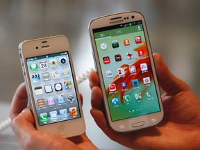 An employee holds Apple's iPhone 4s, left, and Samsung's Galaxy S III at a store in Seoul in this file photo from August 24, 2012. (REUTERS/Lee Jae-Won/Files)