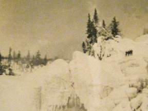 Gigantic ice caves dwarf four men in this 1920s photo of the Lake Superior shoreline.