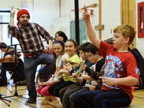 Patti Lamoureaux's singer, dressed in a traditional voyageur toque and sash, shows some of the students how to play the spoons during the performance.
ALAN S. HALE/Daily Miner and News