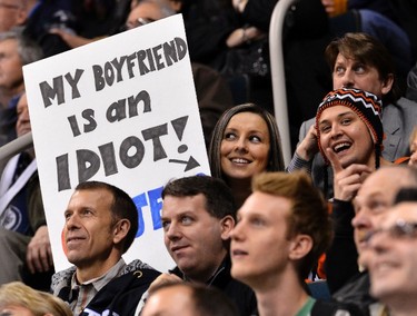 A Winnipeg Jets fan holds a sign next to her boyfriend wearing a Philadelphia Flyers hat during the second period of their NHL hockey game in Winnipeg February 12, 2013. REUTERS/Fred Greenslade  (CANADA - Tags: SPORT ICE HOCKEY)