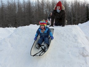 Two-year-old Emerson Spence laughs and shrieks as he tries out the kiddy hill with his mom Brandie Spence at the Chamberlain Family Winter Fun Day.