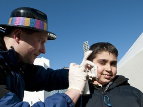 Greg Woudstra, an artist with TempTattoos, gives Rohan Sharma, 9, a spray-painted snowflake tattoo during the Metropolis Edmonton International Winter Festival at Churchill Square, in Edmonton, Alberta, on Feb. 20, 2012. The festival wrapped up on Family Day with both outdoor and indoor activities for the thousands of visitors to the downtown square next to Edmonton's city hall. IAN KUCERAK/QMI AGENCY