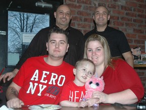 Brian Brinn, front left, and Jennah Priestman with their four-year-old son Weslee Brinn at the St. Thomas Roadhouse Bar and Grill Tuesday night during a fundraiser for Weslee. Behind the family are Roadhouse owners and brothers Dan, left, and Sam Aboumourad. The owners said they expected to easily raise over $3,000 through the event which will go to the family to help pay for care for Weslee who is in need of a heart transplant. (Nick Lypaczewski,Times-Journal)