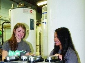 Queen’s egineering students Portia Murray (left), mechanical systems manager, and Leia de Guzman, business manager, work on their team’s total thermal system in the Queen’s Solar Calorimetry Laboratory.The system uses a similar concept to geothermal heating, but is less expensive, easier to install, and more compact.      Rob Mooy - Kingston This Week