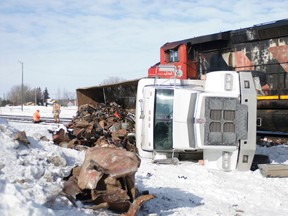 A Truck hauling scrap lays on it's side along the train tracks Thursday, Feb. 14.