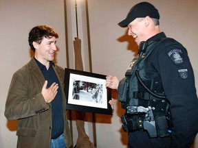Justin Trudeau, front runner in the Federal Liberal leadership race, is presented with a famous photograph, which was taken by former Ottawa Citizen photographer Rod MacIvor, by Belleville Police Cst. Jeff Ling at Loyalist College in Belleville, Ont. Thursday morning, Feb. 14, 2013. The photo, which was taken at 24 Sussex Dr. in Ottawa in 1973, shows Pierre Elliott Trudeau carrying Justin as an RCMP officer, Ling's father, salutes the famous prime minister at the time.  JEROME LESSARD/The Intelligencer/QMI Agency