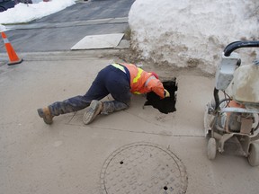 A city worker inspects a sinkhole on Canrobert Street Thursday morning. (HEATHER RIVERS, Sentinel-Review)