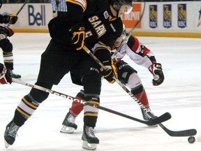 Sarnia Sting defenceman Tyler Hore (in black) fights off checks from Ottawa 67's Daniel Walsh, right during a recent game. Hore will face his old team when the Sting host the Oshawa Generals Saturday.  (PAUL OWEN, The Observer)