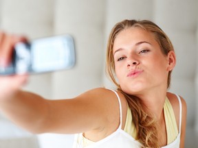 Portrait of a young female taking picture of herself through her cellphone. (SHUTTERSTOCK)