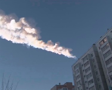 The trail of a falling object is seen above a residential apartment block in the Urals city of Chelyabinsk, in this still image taken from video shot on February 15, 2013. A powerful blast rocked the Russian region of the Urals early on Friday with bright objects, identified as possible meteorites, falling from the sky, emergency officials said. REUTERS/OOO Spetszakaz (RUSSIA - Tags: ENVIRONMENT TPX IMAGES OF THE DAY)