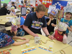 Celebrating becoming 100 days smarter (their first 100 days of school) at Sangudo Community School on Wednesday, Feb. 13, the kindergarten students of teacher, Tammie Vanderwolf, work with her in making necklaces by stringing 100 pieces of Froot Loops cereal. Engaged in stringing or watching are: from left, Anna Briand , Wyatt Chadd, Vanderwolf, (standing watching) Tara Mutton, Niki Hu and (behind Niki) Gaby Sanders.