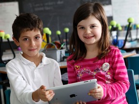 Christopher Andia, left, and Reese Walker, students in Tammy Doyle’s Grade 1 class at St. Thomas More Elementary School, hold an iPad which they use for learning.