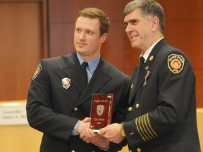Grande Prairie Fire Department Fire Chief Dan Lemieux  (right) hands Kris Adams the Firefighter of the Year award in City Hall, Friday. (Aaron Hinks/Daily Herald-Tribune)