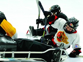 Eight-year-old Kegan Coville, right, flashes a smile after a mid-ice collision during Saturday's sledge hockey exhibition at the Brockville Memorial Centre. NICK GARDINER The Recorder and Times