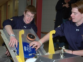 St. Joseph's High School Grade 12 twins Derek, left, and Kevin Webb make adjustments to Rambot, the St. Joe's robotic team's firsbee-throwing creation. The team of about 30 students will compete next month at a provincial event in Waterloo. (Nick Lypaczewski, Times-Journal)