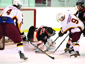 Brockville Tikis goalie Nathan Peters knocks a loose puck away after making a save, as Athens Aeros wingers Brian Berry (4) and Daniel Lacroix search for the rebound during Rideau-St. Lawrence Jr. B playoff action Tuesday night at Centre 76. (STEVE PETTIBONE The Recorder and Times)