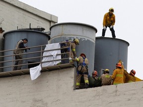 Firefighters work to remove a body found inside a water tank on the rooftop of Hotel Cecil in Los Angeles, California February 19, 2013. (REUTERS/Jonathan Alcorn)