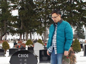 MICHAEL-ALLAN MARION, The Expositor

Elliott Choi stands beside the headstone marking the grave of his father, Byung Soon Choi, at St. George Cemetery.  Korean characters inscribed on the back of the stone contravene a Brant County bylaw.