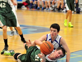 Matti Kohtala, of the Timmins High & Vocational School Blues, reaches over a sprawled Gage Martel, of the O'Gorman Knights, in an effort to get at the ball during the second half of Wednesday's junior boys city basketball championship at TH&VS. The blues posted a 48-21 victory.